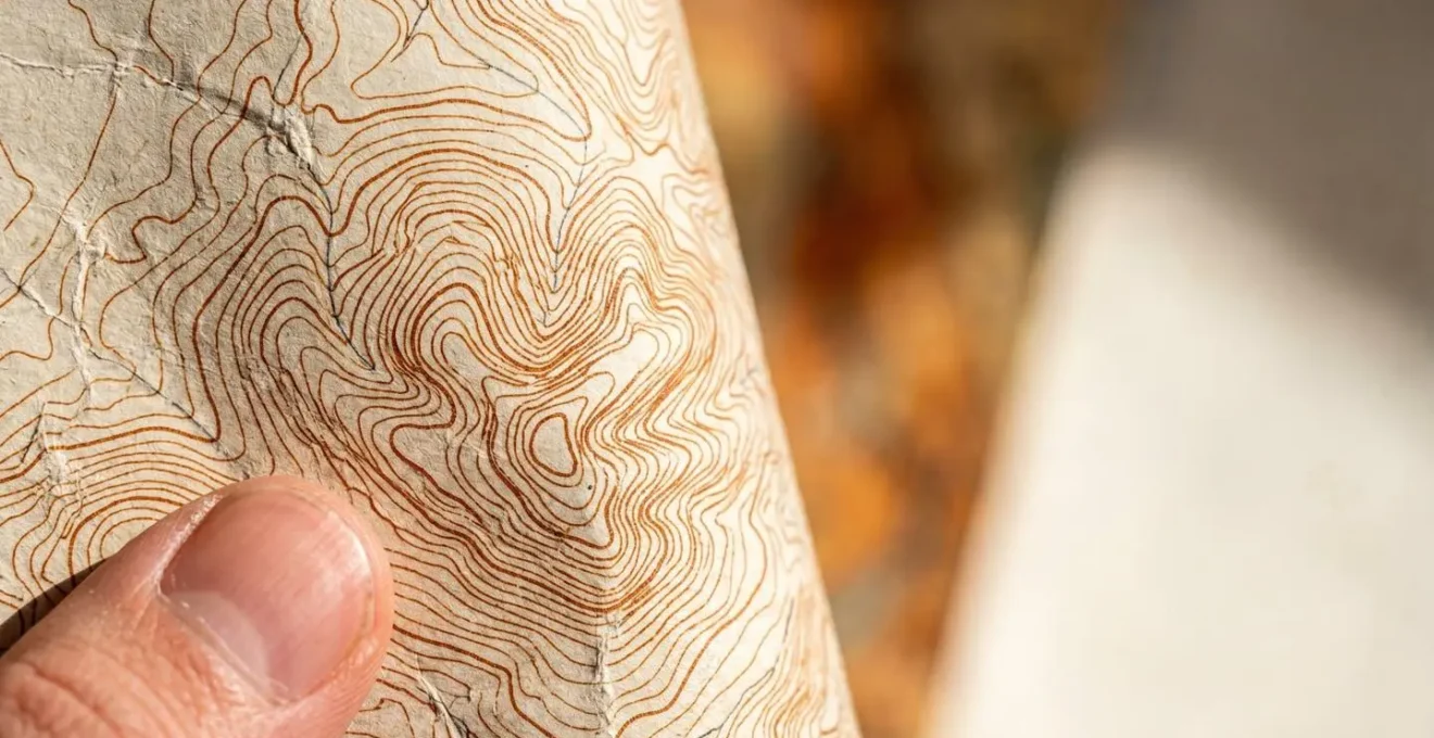 Vue macro de courbes de niveau sur une carte topographique avec texture papier visible et reliefs naturels