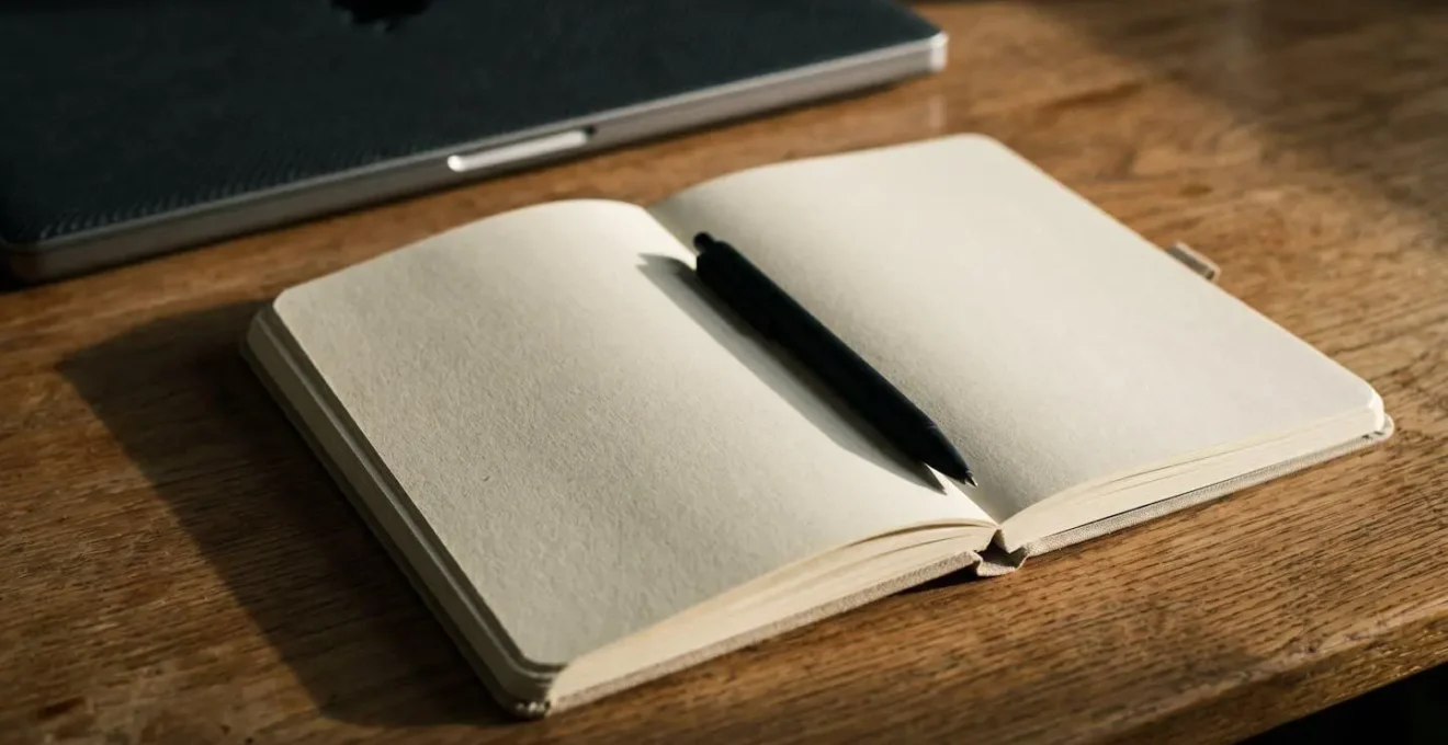 Carnet ouvert avec stylo pose sur un bureau en bois pour le rituel de cloture de journee et liberation mentale